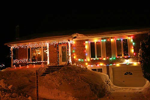 house in heavy snows banks decorated with christmas lights