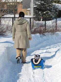 my wife pulling our son in a snow sled