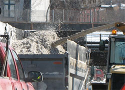 close up of snow being thrown from snowblower into dumptruck